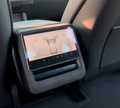 Alcantara ramme monteret omkring bagsædets skærm på midterkonsollen i Tesla Model 3 Highland