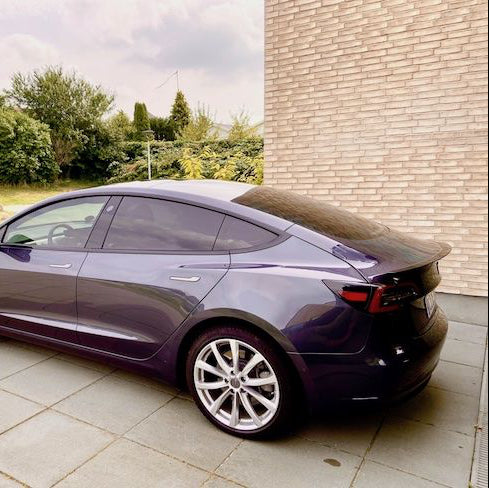 Lilla Tesla Model 3 set fra siden med ABS-spoiler monteret på bagklappen, parkeret udendørs