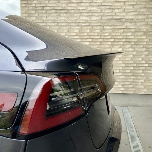 Sort ABS-performance-spoiler med coating monteret på bagklappen af en sort Tesla Model 3, med baglygte synlig