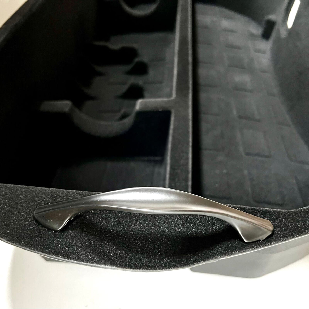 Frunk-opbevaringsboks med metalhåndtag placeret i den forreste bagagerum (frunk) på Tesla Model 3