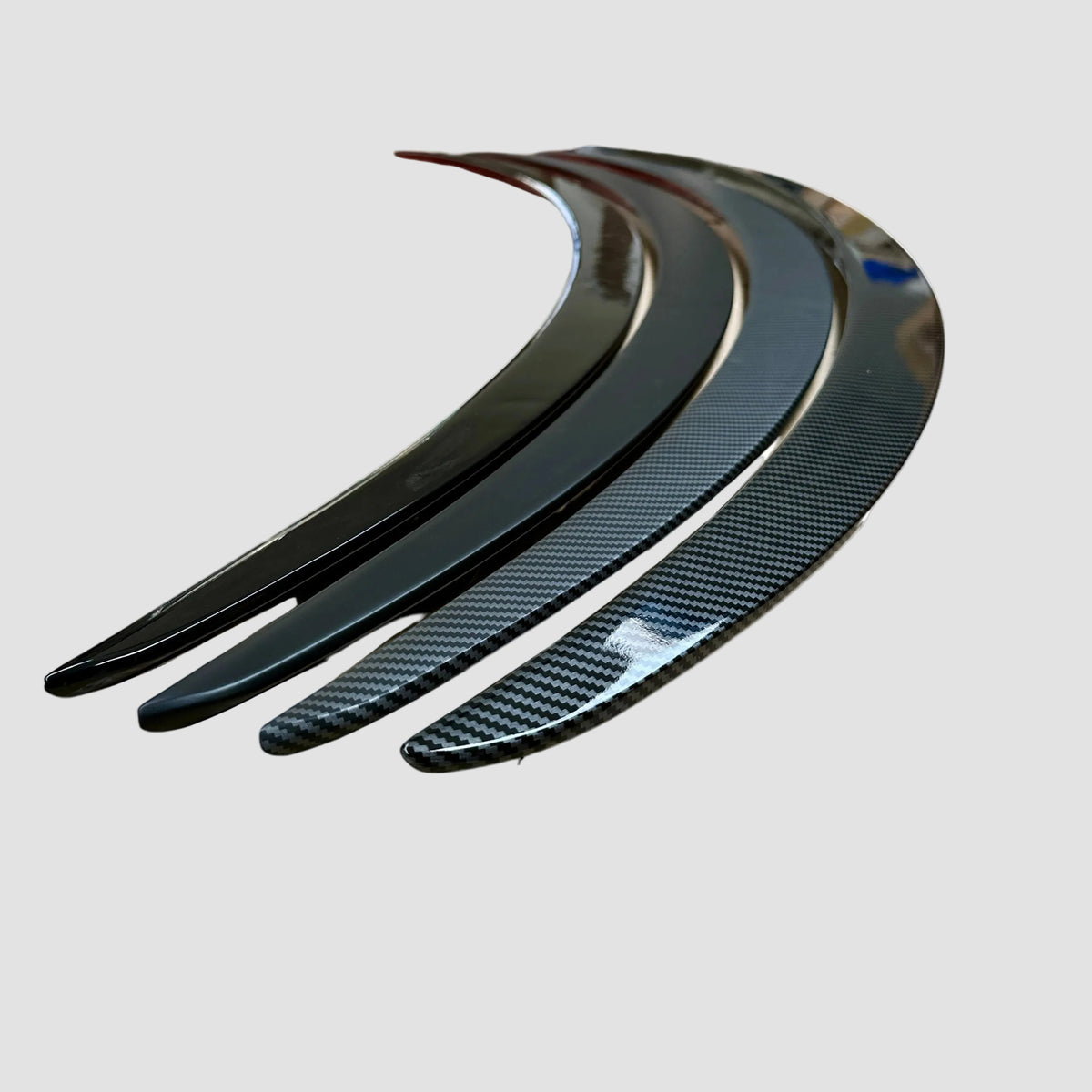 Alle spoiler-varianter i blank sort og carbon-look vist ved siden af hinanden på lys baggrund