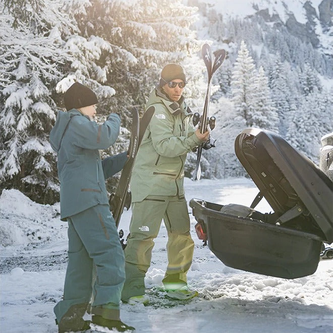 Skiløbere tager ski ud af Thule Arcos XL bagageboks 450L i skoven om vinteren