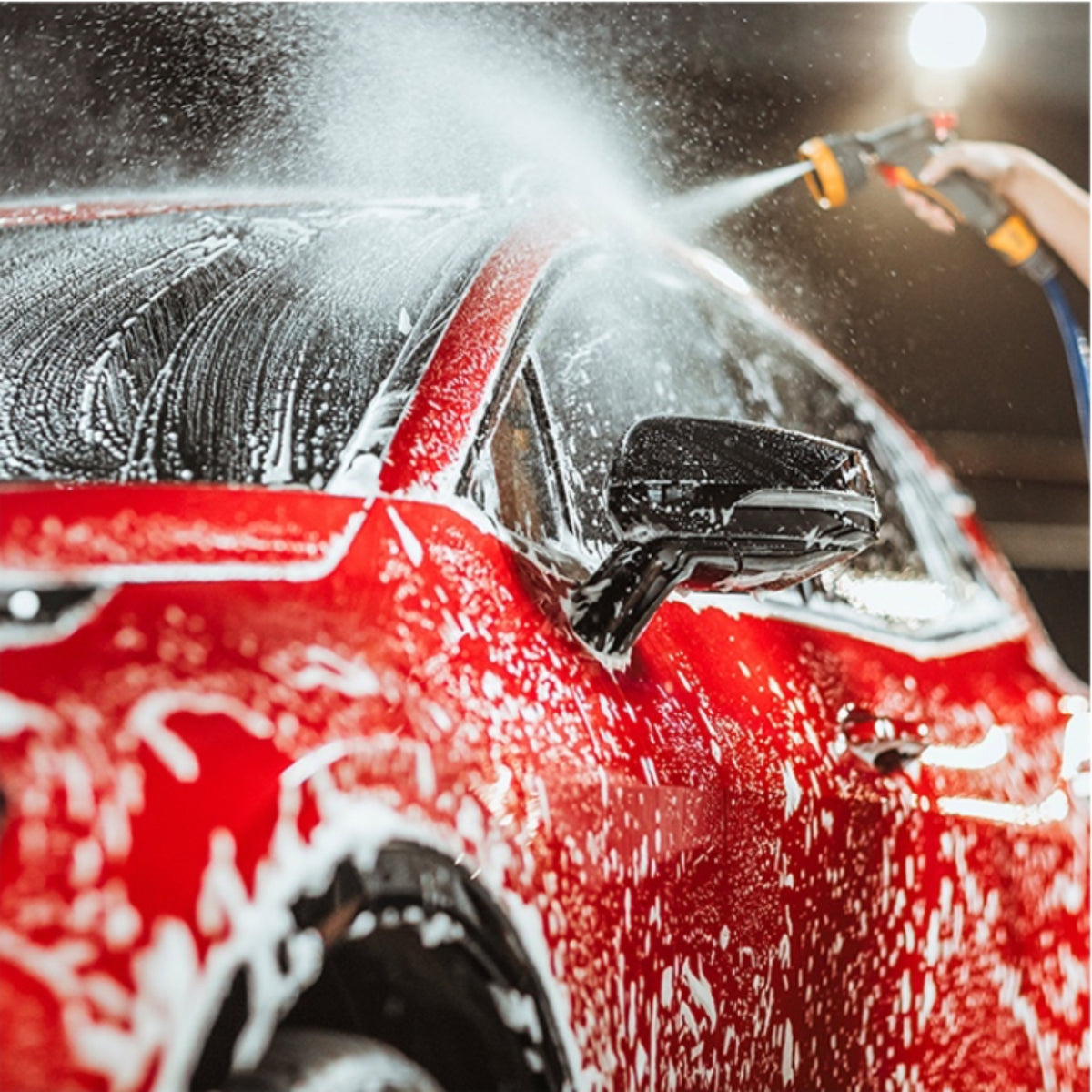 Autoglym Foaming Car Wash Shampoo – rød bil sprøjtes med skum og vand under bilvask, nærbillede af sidespejl