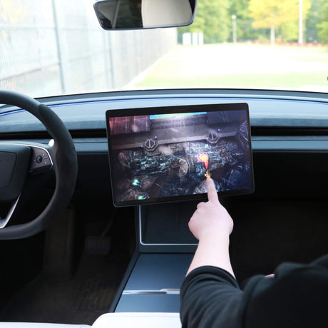 Hånd der spiller et spil på den drejede Tesla-skærm med drejebeslag