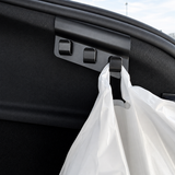 Nærbillede af bagagerumskrog med tre kroge i sort plast, hvor en pose hænger på – Tesla Model Y 2025