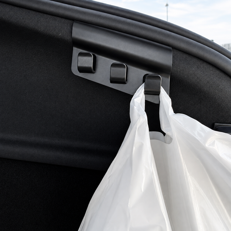 Nærbillede af bagagerumskrog med tre kroge i sort plast, hvor en pose hænger på – Tesla Model Y 2025
