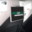 Tablet-holder monteret bag forsædets nakkestøtte i en Tesla med en tablet der viser GreenCarGear-logoet