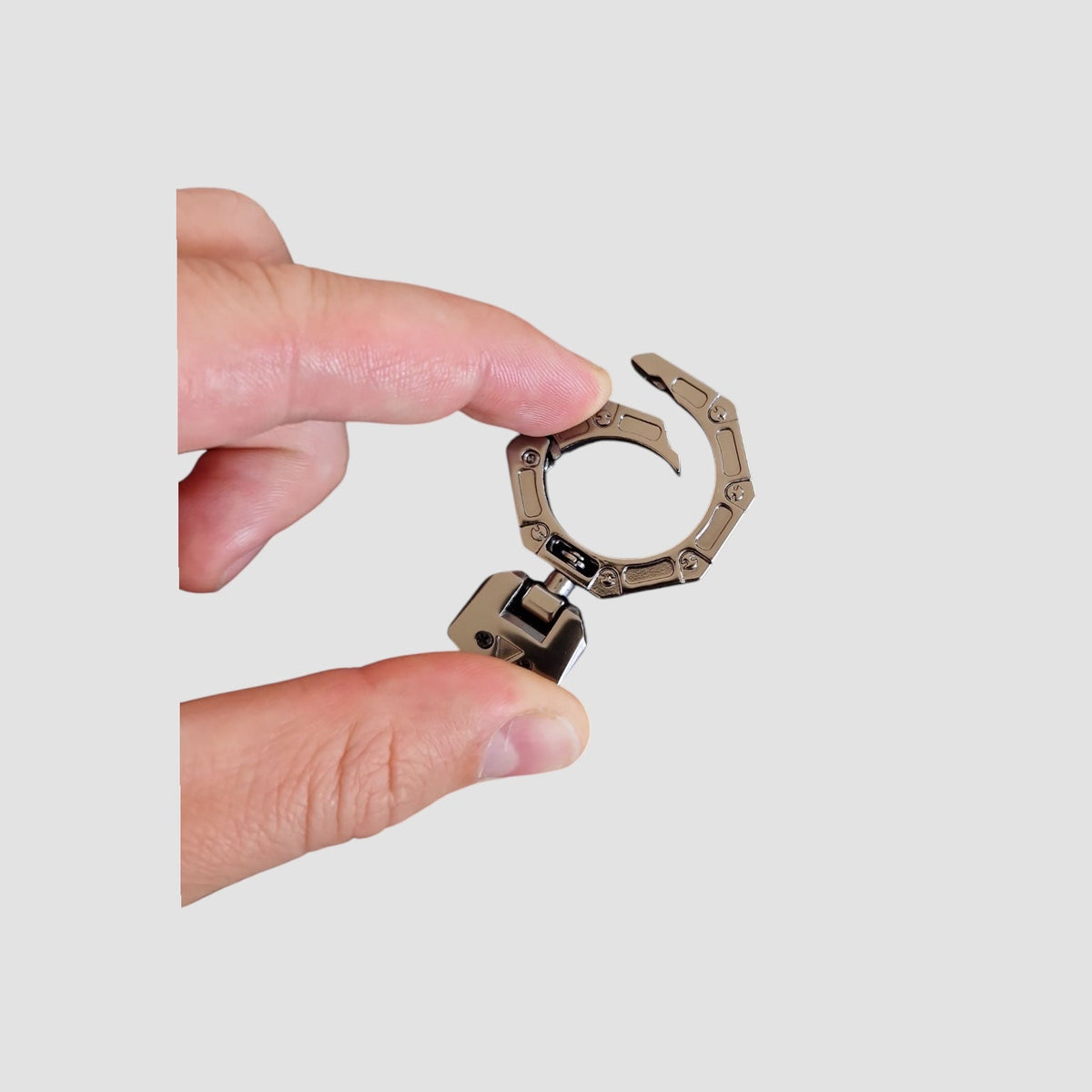 Person holder et nøglecover/ring til Toyota bZ4X mellem to fingre mod en neutral baggrund.