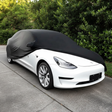 Sort bilcover trækkes over en hvid Tesla Model 3 udendørs