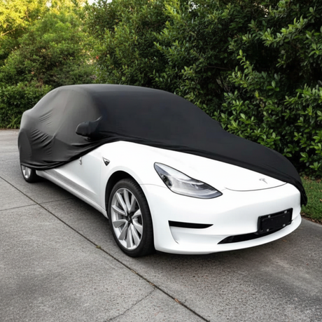 Sort bilcover trækkes over en hvid Tesla Model 3 udendørs