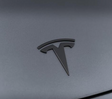 Mat sort Tesla-emblem i metal monteret på Tesla Model 3