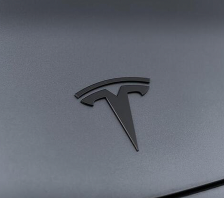 Mat sort Tesla-emblem i metal monteret på Tesla Model 3