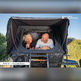 To personer ligger i Moby Mountain Peak XL tagtelt i thunderBlack på Land Rover Defender