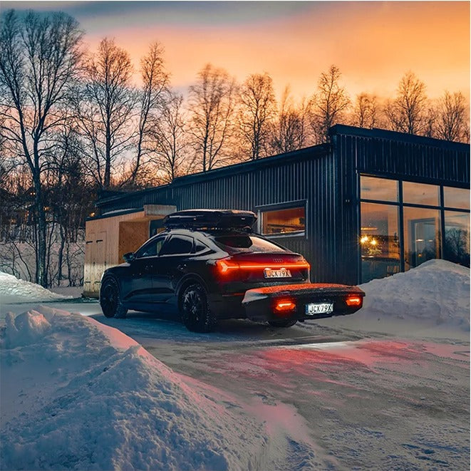 Thule Arcos XL bagageboks 450L monteret på anhængertrækket på en sort elbil i sne ved solnedgang