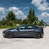 Grå Tesla med en mountainbike monteret på bagklappen med TreeFrog cykelholder udendørs